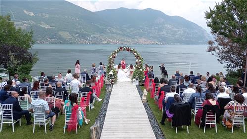 Cerimonia con arco floreale fronte lago, celebrante e sposi